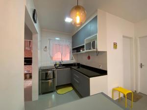 a kitchen with blue cabinets and a yellow stool at Casa em Bertioga condomínio 200 metros da praia in Bertioga