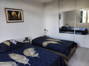 a bedroom with two beds and a mirror at Ancienne Gare 1er étage in Wasselonne