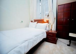 a bedroom with a bed and a dresser and a window at Aduk Guest House Airport City Accra in Otele