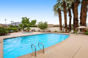 a large swimming pool with palm trees and a building at Sunshine On My Shoulders Permit# STR2022-0160 in Palm Desert