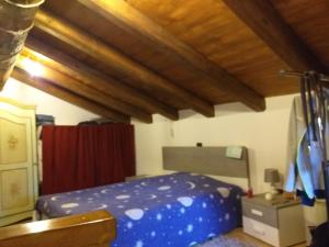 ein Schlafzimmer mit einem blauen Bett und einer Holzdecke in der Unterkunft la casa di nonna pina in Roccasparvera