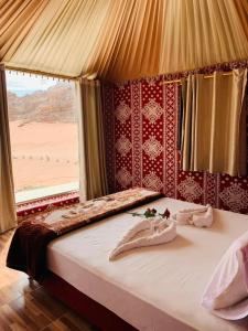 a bed in a room with a view of a desert at Maraheb Luxury camp in Wadi Rum
