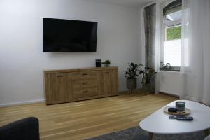 sala de estar con TV de pantalla plana en una pared blanca en APARTMENT SONNE Reusa en Plauen