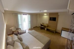 a hotel room with a bed and a desk and a television at Vista Azul Hotel in Pedra Azul