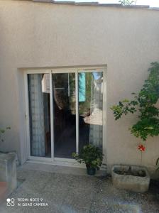 une porte coulissante en verre d'une maison avec deux plantes en pot dans l'établissement Agréable appartement au calme, à Villeneuve