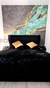 Un dormitorio con una cama negra con una pintura en la pared en Apartamenty Aquarius Gold Boszkowo en Boszkowo