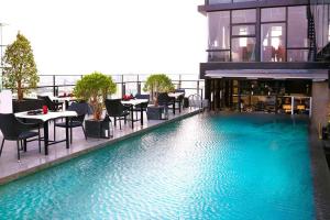 a swimming pool with tables and chairs on a building at The One Sai Gon in Ho Chi Minh City