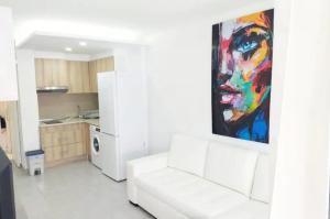ein Wohnzimmer mit einer weißen Couch und einem Gemälde an der Wand in der Unterkunft Playa del Inglés 5 min walk from Yumbo! 304 in Maspalomas