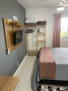 a bedroom with a bed and a tv in a room at Apartamento no Golden Lake - pé na areia, agua de côco e cervejinha in Arraial do Cabo