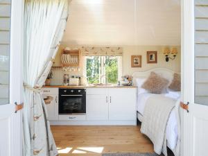 a bedroom with a bed and a kitchen with a window at Orchard Retreat in Crediton