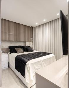 a bedroom with a large bed and a flat screen tv at Refúgio Charmoso e Romântico no Vertigo Premium Studios in Campo Grande