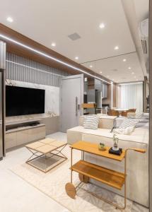 a living room with a large couch and a tv at Refúgio Charmoso e Romântico no Vertigo Premium Studios in Campo Grande
