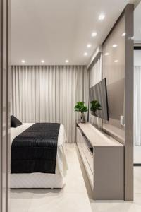 sypialnia z łóżkiem i telewizorem z płaskim ekranem w obiekcie Refúgio Charmoso e Romântico no Vertigo Premium Studios w mieście Campo Grande