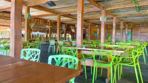 un restaurante vacío con mesas de madera y sillas verdes en On Vacation Amazon en Leticia