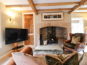 a living room with a fireplace and a tv at Squint Cottage in Skipton