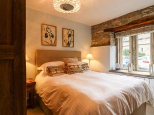 a bedroom with a large white bed with pillows at Squint Cottage in Skipton