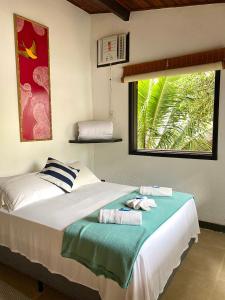 a bedroom with a large bed with towels on it at Pousada Canto Verde in Abraão
