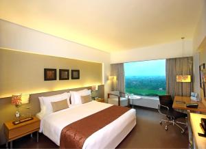 Fortune Select SG Highway, Ahmedabad - Member ITC's Hotel Group في أحمد آباد: غرفه فندقيه بسرير ومكتب ونافذه