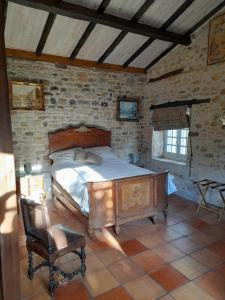 um quarto com uma cama de madeira numa parede de pedra em La petite maison bleue avec piscine em Loubejac