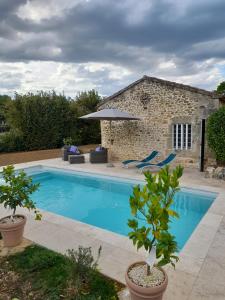 uma piscina em frente a uma casa de pedra em La petite maison bleue avec piscine em Loubejac