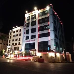 um grande edifício com luzes acesas à noite em 7 Days Hotel em Umm Uthainah