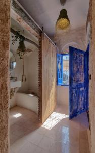 een badkamer met een blauwe deur en een bad bij Casa Amina in Chefchaouene