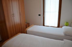 two beds in a small room with a window at Casa Mavignola in Madonna di Campiglio