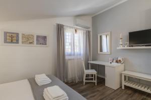 a white room with a bed and a desk with a computer at B&B L'Ulivo Fiumicino in Fiumicino