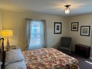 a bedroom with a bed and a chair and a window at Simmons Motel and Suites in Hershey