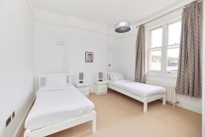 a white bedroom with two beds and a window at The Woolwich Retreat - Enticing 5BDR House with Parking in Woolwich