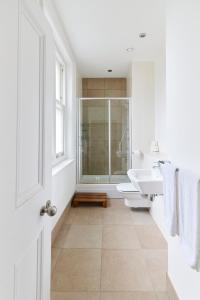 a white bathroom with two sinks and a shower at The Woolwich Retreat - Enticing 5BDR House with Parking in Woolwich