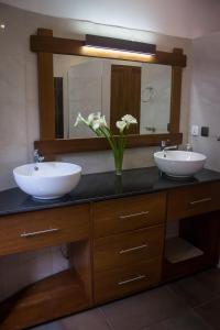 a bathroom with two sinks and a mirror and flowers at The Little Hill Boutique Hotel in Kigali