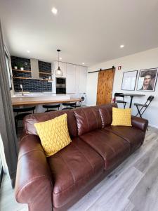 um sofá de couro castanho com almofadas amarelas numa sala de estar em Dona I Apartments at Botanical Garden no Funchal