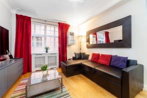 a living room with a leather couch and red curtains at Lovely 1BDR flat in the Heart of London - Mayfair in London