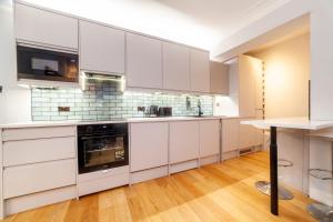 a kitchen with white cabinets and a wooden floor at Lovely 1BDR flat in the Heart of London - Mayfair in London