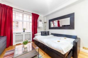 a bedroom with a large bed with red curtains at Lovely 1BDR flat in the Heart of London - Mayfair in London