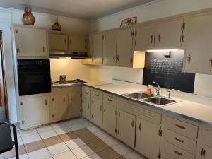 a kitchen with white cabinets and a sink at Simmons Motel and Suites in Hershey