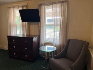 a living room with a chair and a dresser and a television at Simmons Motel and Suites in Hershey