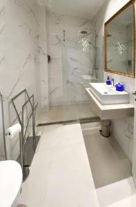 a white bathroom with a sink and a mirror at SUITES SAN ESTEBAN 16 Real in Seville