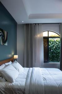 a bedroom with a white bed and a window at The Little Hill Boutique Hotel in Kigali