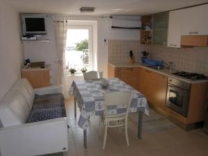 a small kitchen with a table and a couch at Apartment Haramina in Baška