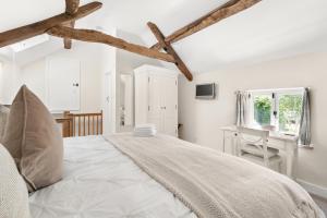 um quarto branco com uma cama grande e uma secretária em Rose End Cottage, a Luxury Getaway em Adlestrop