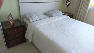 a bedroom with a large white bed and a night stand at Bora Bora Barra Resort in Rio de Janeiro
