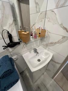 a white bathroom with a sink and a mirror at London Apartments - Free parking in Katowice