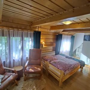 a bedroom with a bed and a chair at Domek pod Brzozami - zniżki na Termy Bania! in Czarna Góra