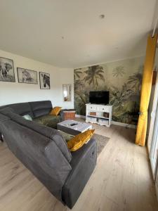 Una sala de estar con un sofá y un televisor. en SUPERBE HAUT DE VILLA AVEC VUE SUR LA MER, en Vence
