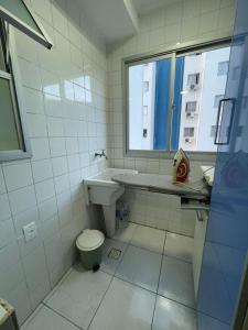 La salle de bains est pourvue d'un lavabo, de toilettes et d'une fenêtre. dans l'établissement Ap aconchegante 12 min a pé p Praia, à Praia Grande