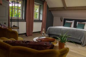 a bedroom with a bed and a couch and a table at Landhuis Hotel de Hilkensberg in Broekhuizen