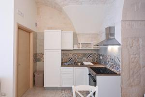 een kleine keuken met witte kasten en een spoelbak bij Casa vacanze nonna donata in Martina Franca