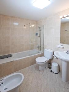 a bathroom with a toilet and a tub and a sink at MC Apartments in Puerto del Rosario